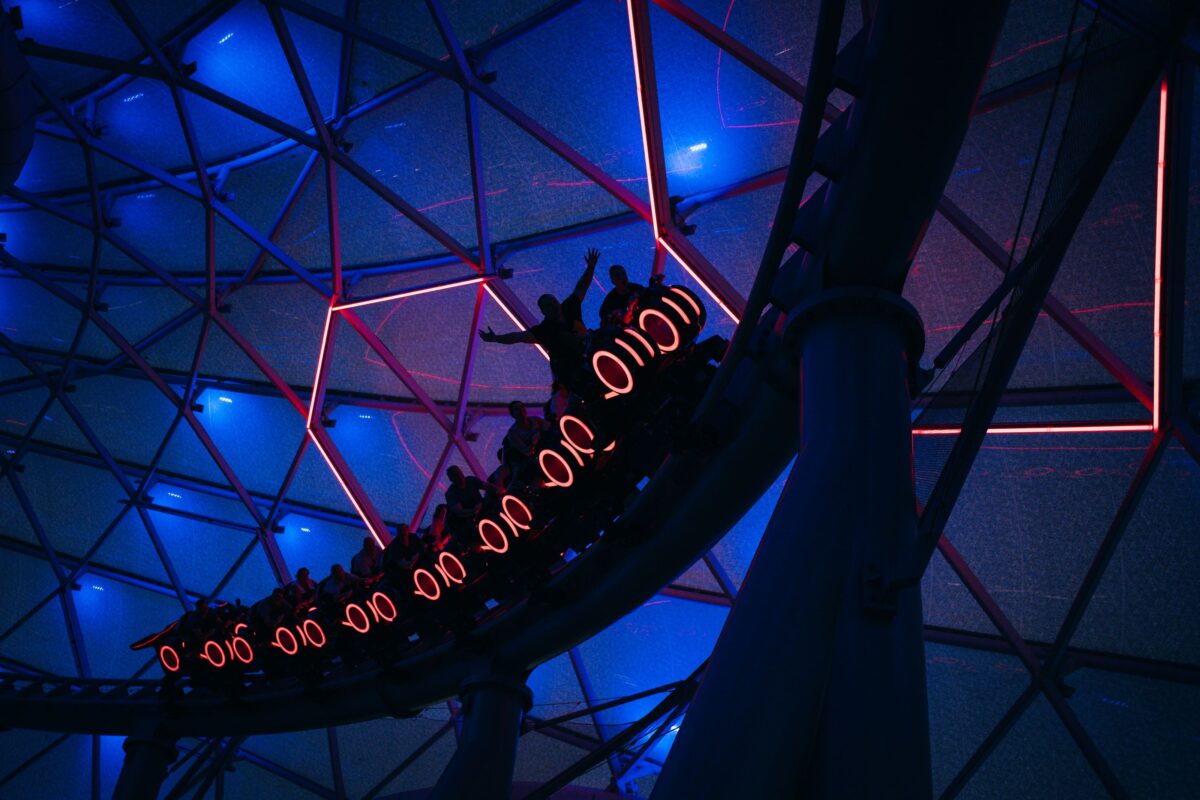 Silhouette de montagnes russes illuminées la nuit, evoquant Space Mountain