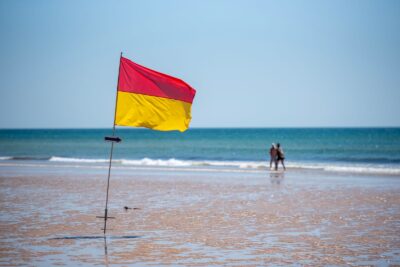 Drapeau de baignade bicolore rouge et jaune planté sur une plage